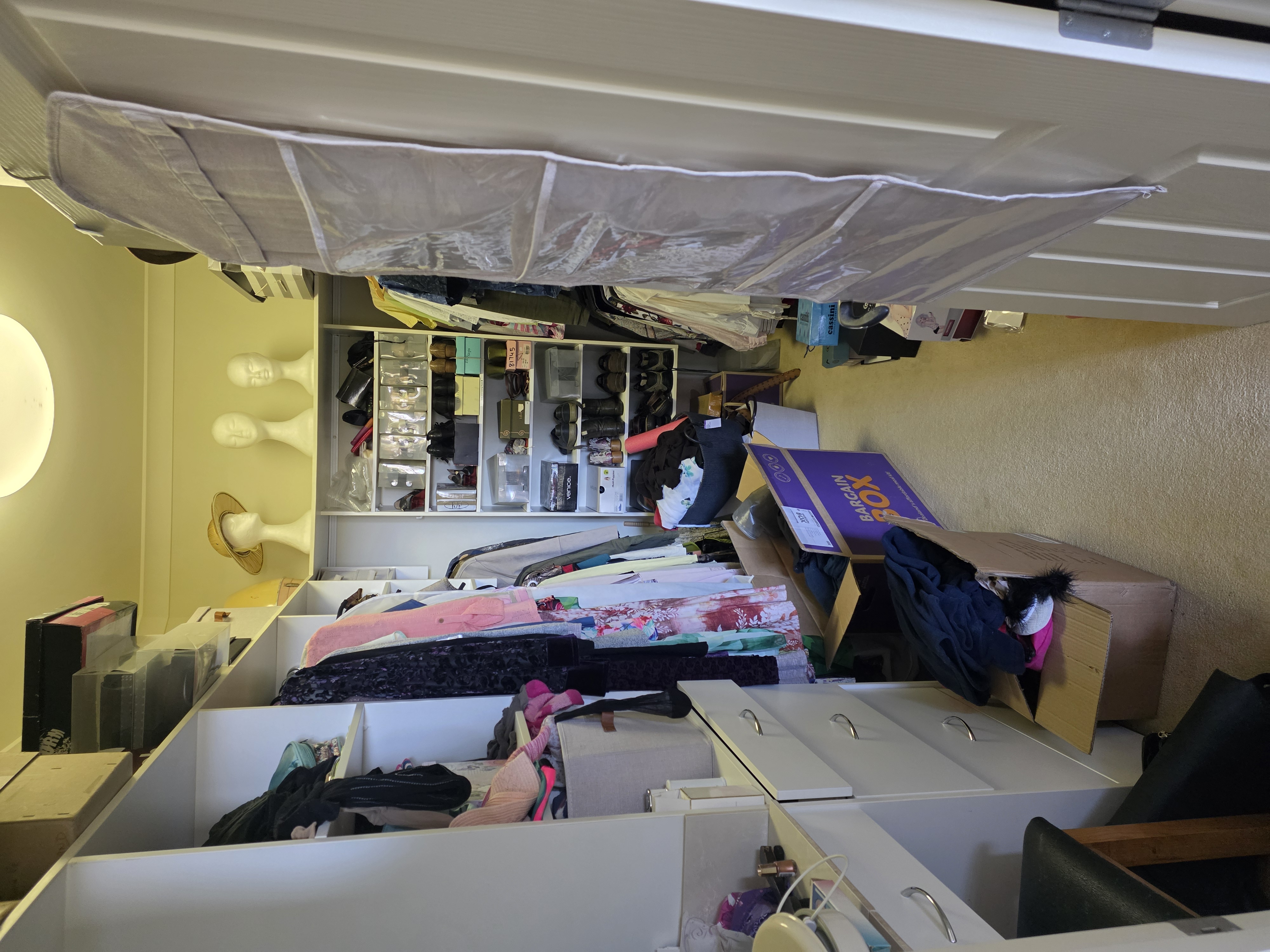 A wardrobe filled with hanging clothes, shelves and boxes